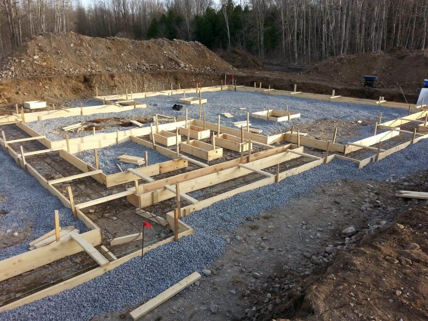 Wooden frames set up on a gravel foundation for a building.