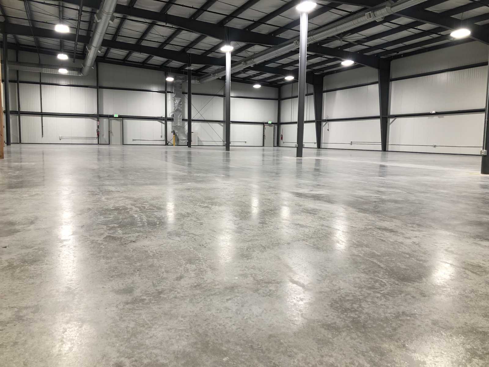 Empty industrial warehouse with polished concrete floor and high ceilings.